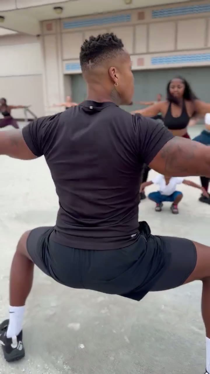 Coach Mac leading a rooftop bootcamp class through a squat hold